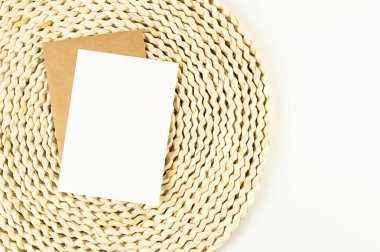 Kahverengi hasır masa paspasının üst görüntüsü, beyaz arka planda beyaz ve kahverengi kartlar. Saman yuvarlak tepsi, düz konum, kopyalama alanı. 