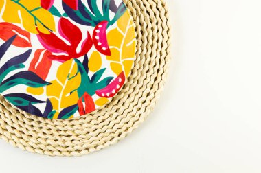 Kahverengi hasır masa paspasının üst görüntüsü, beyaz arka planda renkli plaka. Saman tepsisi, egzotik bitki tabağı, yaz pikniği. Düz yat, boşluğu kopyala. 