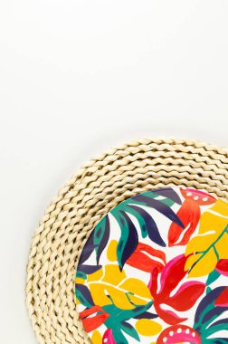 Kahverengi hasır masa paspasının üst görüntüsü, beyaz arka planda renkli plaka. Saman tepsisi, egzotik bitki tabağı, yaz pikniği. Düz yat, boşluğu kopyala. 