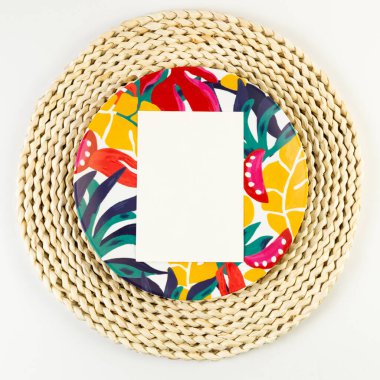 Kahverengi hasır masa paspası, beyaz kart, beyaz arka planda renkli plaka. Saman tepsisi, egzotik bitki tabağı, yaz pikniği. Düz yat, boşluğu kopyala. 