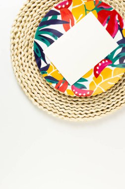 Kahverengi hasır masa paspası, beyaz kart, beyaz arka planda renkli plaka. Saman tepsisi, egzotik bitki tabağı, yaz pikniği. Düz yat, boşluğu kopyala. 