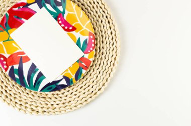 Kahverengi hasır masa paspası, beyaz kart, beyaz arka planda renkli plaka. Saman tepsisi, egzotik bitki tabağı, yaz pikniği. Düz yat, boşluğu kopyala. 