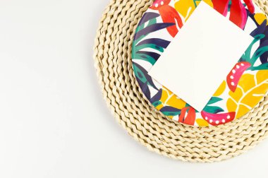 Kahverengi hasır masa paspası, beyaz kart, beyaz arka planda renkli plaka. Saman tepsisi, egzotik bitki tabağı, yaz pikniği. Düz yat, boşluğu kopyala. 