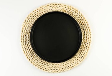 Kahverengi hasır masa paspası, beyaz arka planda siyah plaka. Saman yuvarlak tepsi, düz konum, kopyalama alanı. 