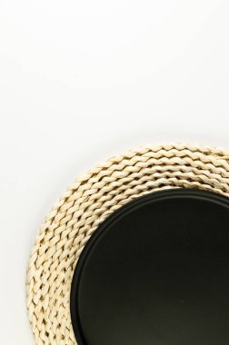 Kahverengi hasır masa paspası, beyaz arka planda siyah plaka. Saman yuvarlak tepsi, düz konum, kopyalama alanı. 