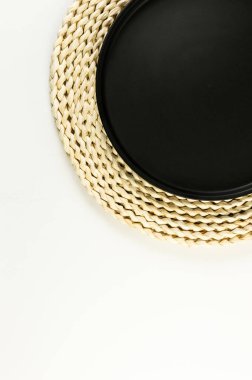 Kahverengi hasır masa paspası, beyaz arka planda siyah plaka. Saman yuvarlak tepsi, düz konum, kopyalama alanı. 