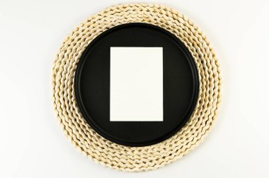 Kahverengi hasır masa paspası, siyah plaka, beyaz arka planda beyaz kart. Saman yuvarlak tepsi, düz konum, kopyalama alanı. 