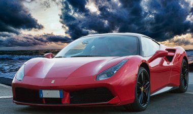 Roma, İtalya - 22 Kasım 2022: Hızlı ve lüks spor araba Ferrari 488 GTB Ferrari İtalyan otomobil üreticisi fantastik mavi saat günbatımı ve dramatik gökyüzü ile deniz kenarında yer aldı
