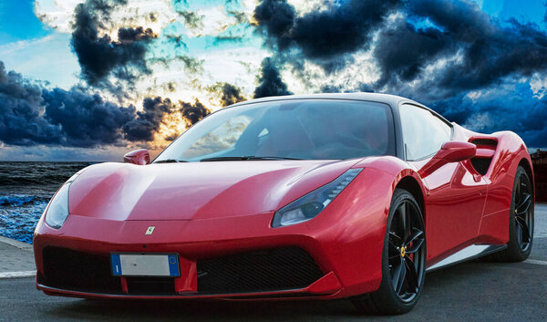 Рим, Италия - 22 ноября 2022: Быстрый и роскошный спортивный автомобиль Ferrari 488 GTB от итальянского автопроизводителя Ferrari, расположенный в фантастическом синем часе заката с впечатляющим небом
