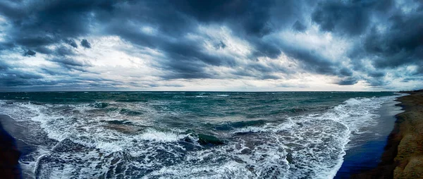 嵐の海の波が多くの海の泡で海岸でクラッシュを脅かすとビーチのパノラマビューでのニンボストラタス雲と悪天候と劇的な曇りの空 ストック画像