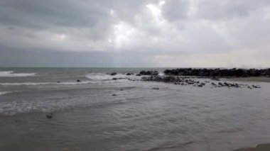 Dalgalı denizde deniz manzarası ve gri bulutların arasındaki güneş ışığı kötü havayı tehdit ediyor.
