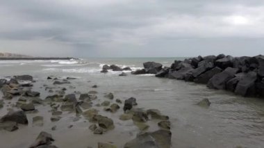 Sert deniz ve dramatik gökyüzü dalgalarıyla kayalık körfezdeki manzara kötü hava dalgaları rüzgarla çalkalanan deniz dalgalarını durdurur