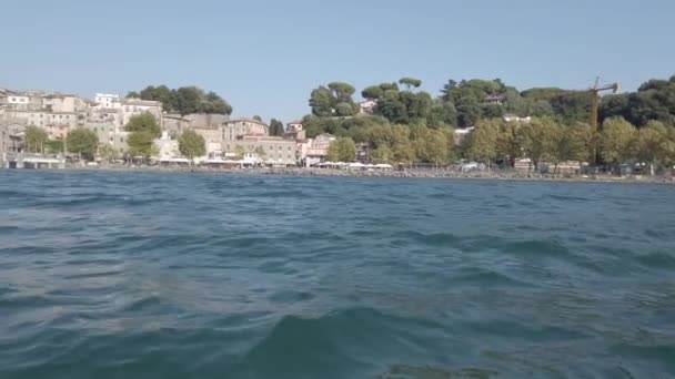Kayak Pov俯瞰着美丽古老的村庄Anguillara Sabazia的城市天际 它座落在布拉卡诺湖畔 绿意盎然 绿意盎然 蔚蓝碧绿的湖水 — 图库视频影像