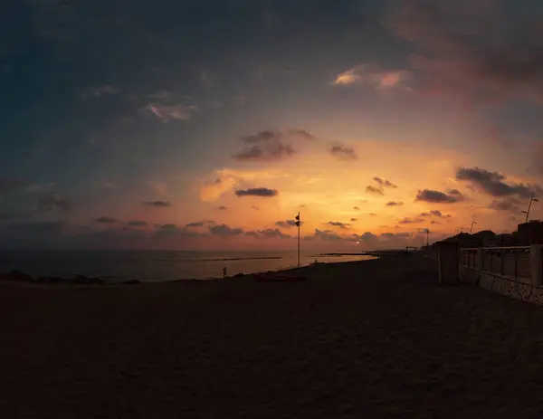 stock image Immersive panoramic sunset on the Roman beach with stunning pastel colored Sky between fantastic softly clouds hues of pink, orange and gold in a serene day