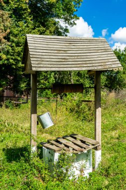 Temiz içme suyu için uzun zamandır dövülmüş demir kovayla eski bir kuyu çatısı olan eski bir fotoğrafçılık, büyük kovada temiz su, eski kuyudan gelen alüminyum kovada kaynak suyu.
