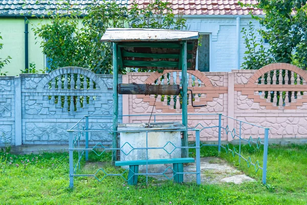 Temiz içme suyu için uzun zamandır dövülmüş demir kovayla eski bir kuyu çatısı olan eski bir fotoğrafçılık, büyük kovada temiz su, eski kuyudan gelen alüminyum kovada kaynak suyu.