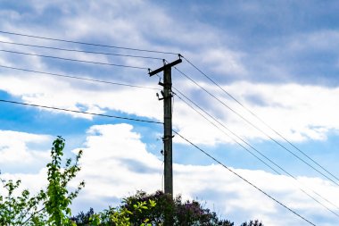 Renkli arka planda kablo olan elektrik direği yakın planda, elektrik direği ile gökyüzünün altında halat kablosu, konut binaları için elektrik direği hattı kablosu.
