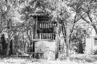 Temiz içme suyu için uzun zamandır dövülmüş demir kovayla eski bir kuyu çatısı olan eski bir fotoğrafçılık, büyük kovada temiz su, eski kuyudan gelen alüminyum kovada kaynak suyu.