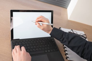 Yetenekli bir profesyonel, çağdaş bir çalışma ortamı içinde parlak bir dizüstü bilgisayarda dijital bir kalem kullanıyor.