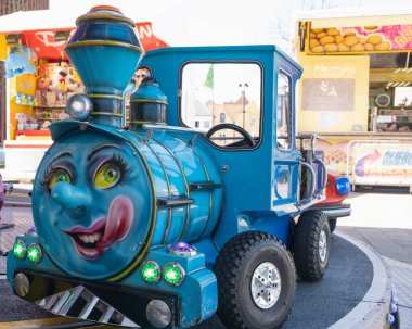 Fuarlarda ve karnavallarda çocukların eğlenmesi için tasarlanmış neşeli yüzlü renkli bir tren.