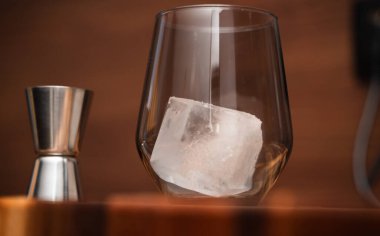 Kokteyl aşıkları ve hayranları için ideal bir jigger yanında büyük bir buz küpü bulunan sofistike bir viski bardağı.