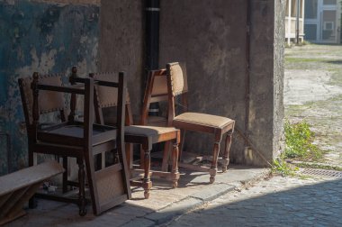 Bu görüntü, sıcak güneş ışığıyla yıkanmış klasik ahşap sandalyelerin yer aldığı sakin bir köşe yakalıyor. Nostalji ve sessiz yansımayı çağrıştıran sakin bir atmosfer yaratıyor..