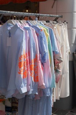 Değişik renkler ve tasarımlar sergilenen canlı bir gömlek koleksiyonu bir market tezgahında asılı, yaz modası ilham kaynağı ve şık kıyafetler için mükemmel.