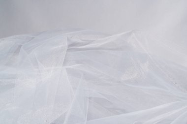 Bu, çok güzel beyaz bir tül kumaşın dokusunu ve zarafetini vurgulayan detaylı bir yakın çekim görüntüsü.