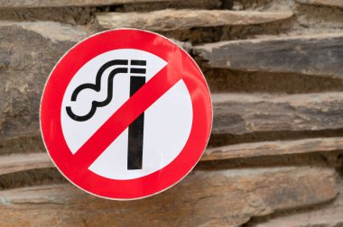 Görünürde belirgin, net bir sigara içilmeyen tabela tam görünürlük için kırsal taştan bir arka plan üzerine kurulmuş.