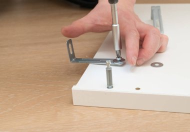 Becerikli bir el, düz bir yüzey üzerinde çeşitli mobilya bileşenlerini dikkatlice birleştirmek için titiz bir araç kullanır.