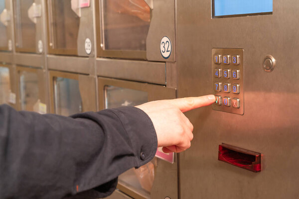 Человек уверенно нажимает кнопку, на которой отображается номер 32, возможно, связанный с находящимися поблизости предметами.