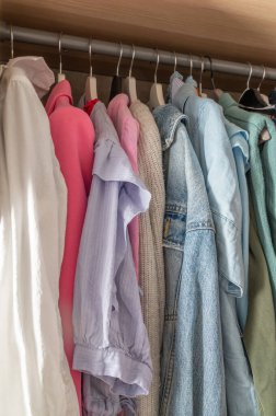 Modern ve şık bir gardıroba asılmış şık gömleklerden oluşan canlı ve renkli bir seçim.