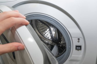 Ön yükleme makinesinin kapısını açan kişinin yakın plan fotoğrafı.