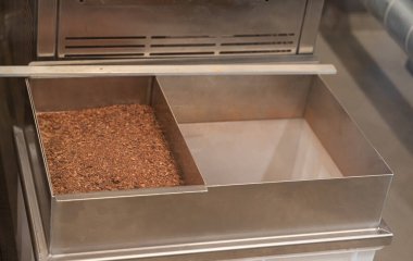 Parlak paslanmaz çelik bir kap ağzına kadar kahverengi taneciklerle doludur. Mutfakta veya atölyede çeşitli kullanımlar için hazırdır.