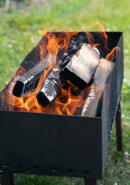 Dans eden alevler, mangal kömürünün etrafını sarar. Açık hava yemekleri ve toplantılar için zemin hazırlar.