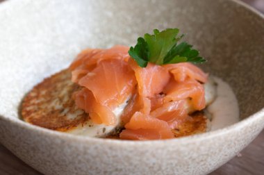 Taze maydanozla süslenmiş lezzetli tütsülenmiş somonlarla süslenmiş güzel düzenlenmiş bir yemek kasesi.