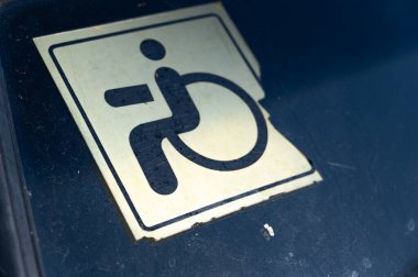 Arabanın ön camındaki soluk tekerlekli sandalyeye erişim sembolünü gösteren bir görüntü engelli erişimini vurguluyor.