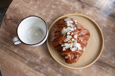 Taze pişmiş kruvasan, enfes bir tabağın üzerine, bir fincan aromatik kahvenin yanına yerleştirilmiş. Kahvaltıdan zevk almak için mükemmel.