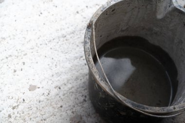 Tamamen suyla dolu bir kovanın yakından görüntüsü, desenli beton zemin yüzeyinde nazikçe dinleniyor.