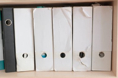 Bir raf üzerinde farklı durum ve durumları gösteren çeşitli belge klasörlerinin bir koleksiyonu