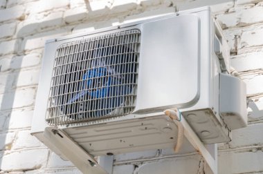 Modern bir havalandırma ünitesi tuğla bir duvara monte edilir ve yaşam alanı için gerekli soğutmayı sağlar.