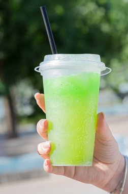 Canlı, ferahlatıcı yeşil bir içecek şeffaf bir bardakta ustaca servis edilir, sıcak yaz günlerinde keyif almak için idealdir.