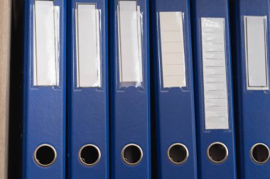 Bir ofis ortamında belge ve dosyaları düzenlemek için ideal düzenlenmiş mavi klasörler koleksiyonu.