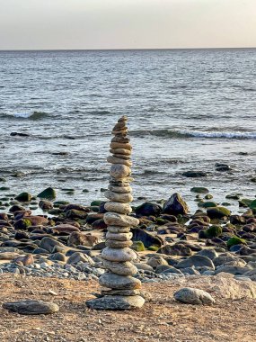 Gran Canaria, Kanarya Adaları 'ndaki kayalık bir sahilde dengeli bir taş yığını. Huzurlu okyanus dalgaları ve gün batımı huzurlu ve meditasyon yapan bir kıyı manzarası yaratır..
