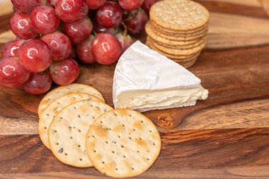 Lezzetli bir krem peynirli peynir, çıtır kraker ve ahşap servis tahtasına yerleştirilmiş taze kırmızı üzümler gurme ya da şarap eşleştirme için mükemmel.
