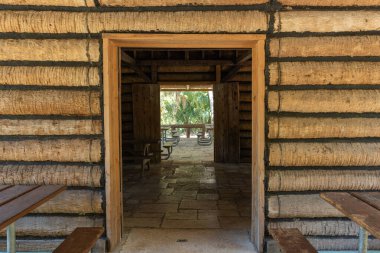 Kırsal ahşap kulübe duvarına yakın çekim. Çevresi yeşil ormanlarla çevrili, güneş ışığıyla çevrili klasik bir pencere var. 