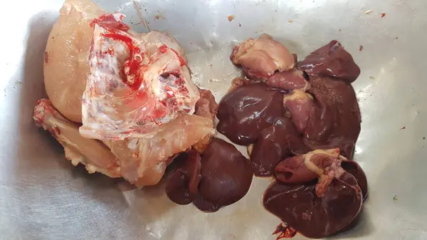 Çiğ tavuk ciğeri ve tavuk ciğeri beyaz tabakta.