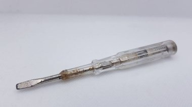 Beyaz arka planda paslı metal tornavida.