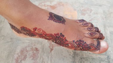 Ayağında gri bir arka planda dövmesi olan güzel bir kadın eli.