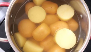 Soyulmuş patatesler metal kapta kaynıyor: Pişirme Süreci Üst Görünümü